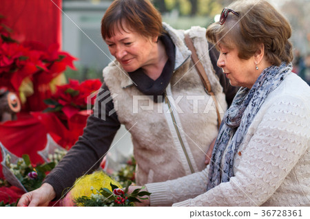 mature women considering decorations at Christmas market mature women considering decorations at Christmas market 36728361