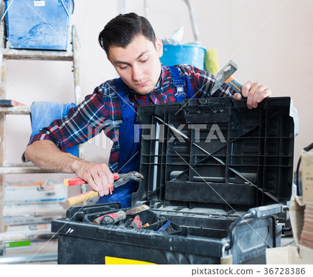 Worker looking for necessary tool in toolbox 36728386