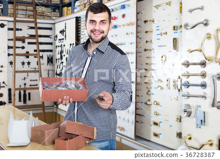 male seller sorting boxes with door handles in houseware shop 36728387