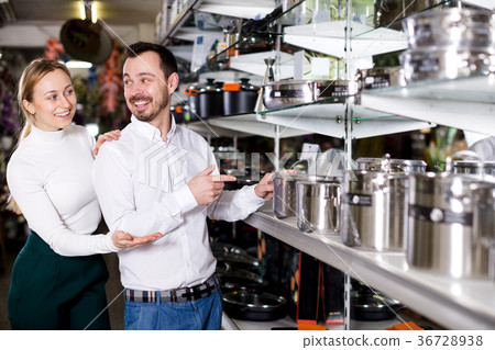 Couple examining various saucepans in dinnerware store 36728938