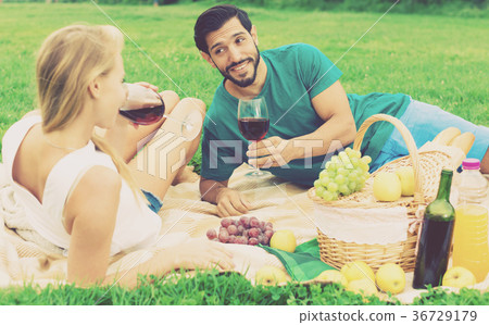 Smiling couple is lying with wineglasses and talking 36729179