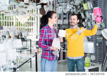 Family of two in shop of home appliances are choosing night lamp 36729549