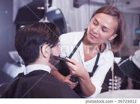 woman hairdresser shaving man's beard in barbershop woman hairdresser shaving man's beard in barbershop 36729912