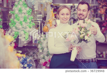 Glad loving couple deciding on flower decoration 36729948
