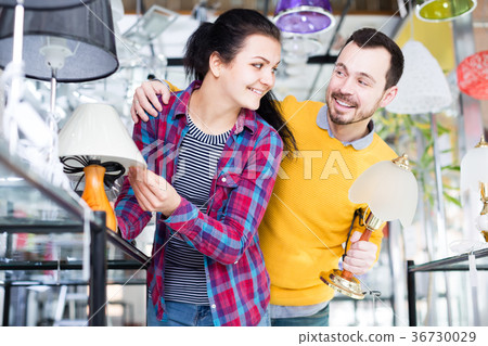 Man and woman viewing assortment of table lamps Man and woman viewing assortment of table lamps 36730029