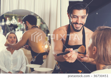 Cheerful male makeup artist applying cosmetics Cheerful male makeup artist applying cosmetics 36730451