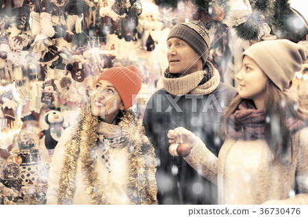 Family couple with teen girl choosing Christmas decoration Family couple with teen girl choosing Christmas decoration 36730476