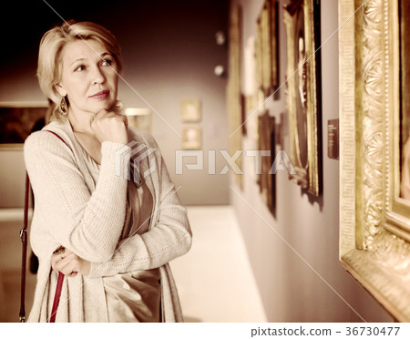 Mature woman in art museum near the painting Mature woman in art museum near the painting 36730477