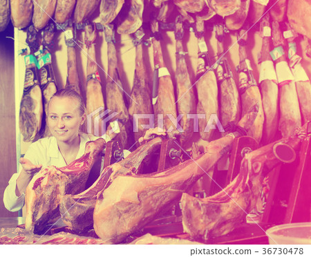Woman seller wearing uniform showing iberian ham Woman seller wearing uniform showing iberian ham 36730478