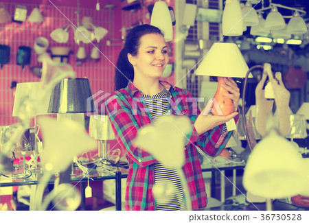 Positive girl choosing stylish and modern lamp Positive girl choosing stylish and modern lamp 36730528