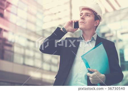 Smiling architect in helmet talking phone 36730540