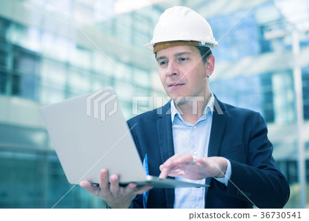 Smiling man in helmet working at the laptop Smiling man in helmet working at the laptop 36730541
