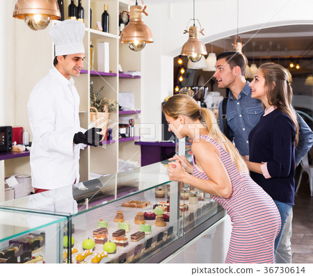 Man is offering delicious cakes from showcase 36730614