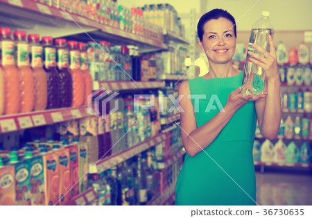 Portrait of positive female buying water in bottle 36730635