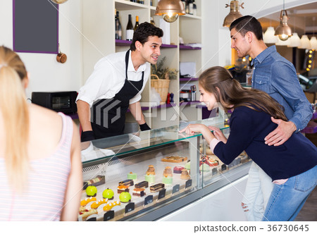 Family couple with female friend are choosing delicious cakes from showcase 36730645
