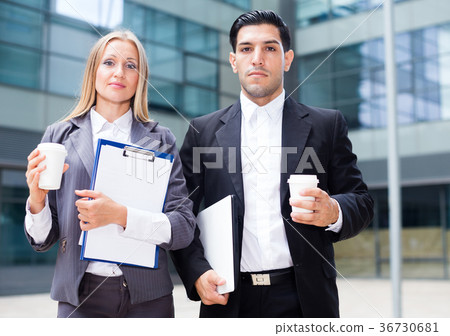 Businesswoman and her partner are standing with folder and coffee Businesswoman and her partner are standing with folder and coffee 36730681