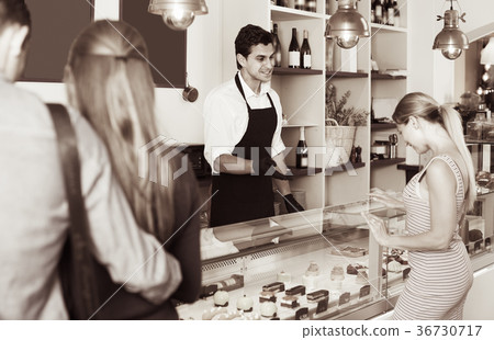 Clients are choosing delicious cakes from showcase 36730717