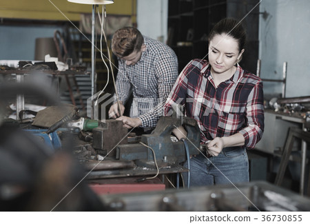 Girl worker is standing near vise equipment in workshop. 36730855