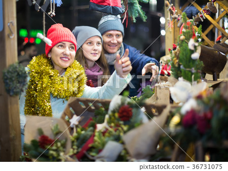 interested middle-aged married couple with a teenage daughter at Christmas market 36731075