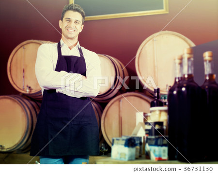 Happy man winery expert in uniform standing in shop 36731130