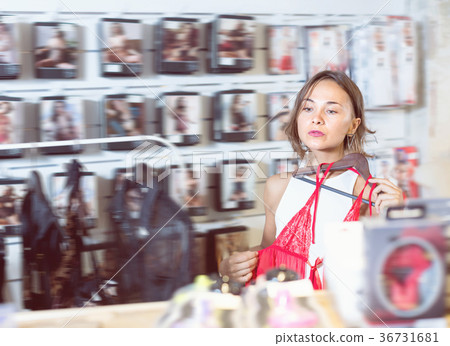 Female purchaser touching sexy red clothes in the modern sex sho 36731681