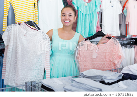 Young woman shopper choosing garments at sales 36731682