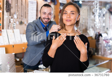 male worker helps to trying chainlet with pendants 36731760