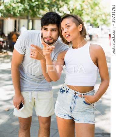 Man and woman talking and pointing finger at the street 36731763