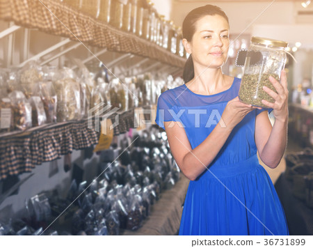 adult female choosing natural dried herbs sold by weight in eco shop 36731899