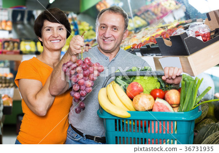 Happy family standing with basket with vegetables and fruits Happy family standing with basket with vegetables and fruits 36731935