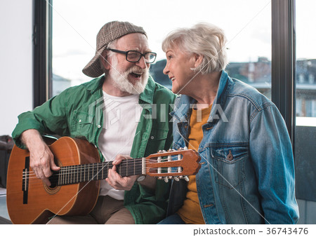 Playful aged couple relaxing at home with musical Playful aged couple relaxing at home with musical 36743476