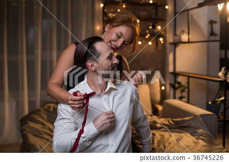 Joyful woman untying bow of ardent man in bedroom Joyful woman untying bow of ardent man in bedroom 36745226