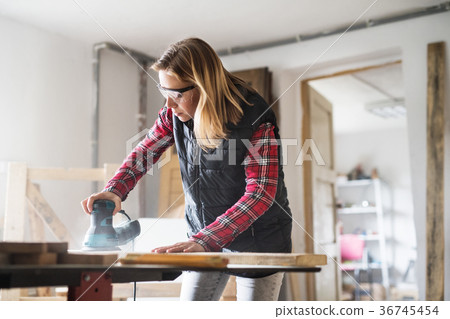 Young woman worker in the carpenter workroom. Young woman worker in the carpenter workroom. 36745454