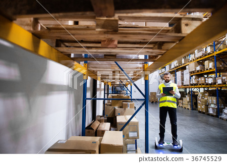 Male warehouse worker on hoverboard. Male warehouse worker on hoverboard. 36745529