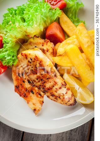 Grilled chicken breasts served with fries Grilled chicken breasts served with fries 36748490