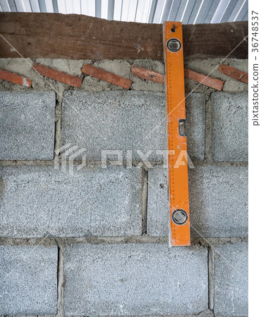Old level ruler is hanging on the brick wall. 36748537