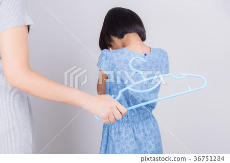 Mother punishing daughter by hitting with a hanger 36751284