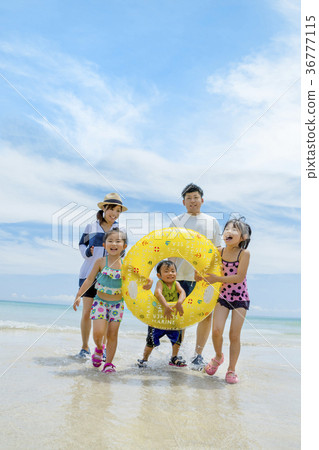 Family of five playing with floats at summer seaside 36777115