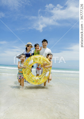 Family of five playing with floats at summer seaside 36777126