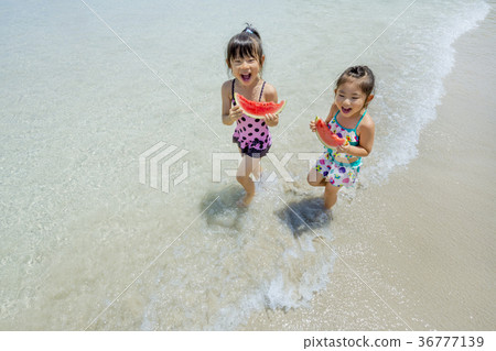 Sisters walking along the summer seaside with watermelon Sisters walking along the summer seaside with watermelon 36777139