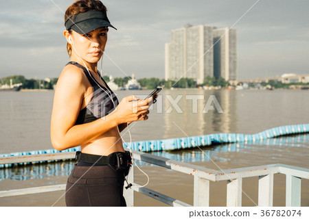 Sporty Woman listening to music with earphones Sporty Woman listening to music with earphones 36782074