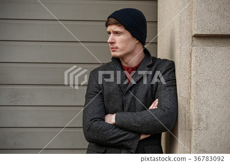 Serious young male standing against wall Serious young male standing against wall 36783092