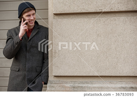 Cheerful young man talking on phone and smiling Cheerful young man talking on phone and smiling 36783093