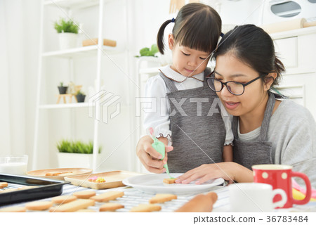 Asian Kid and young mother decorating cookie. Asian Kid and young mother decorating cookie. 36783484
