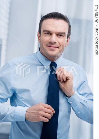 Cute nice man checking his tie Cute nice man checking his tie 36789413