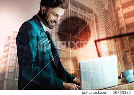 Cheerful businessman working on laptop and smiling Cheerful businessman working on laptop and smiling 36790883