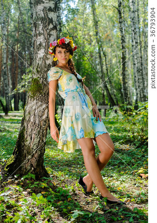 Beautiful girl in wreath of flowers near birch Beautiful girl in wreath of flowers near birch 36793904
