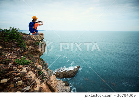 Young woman hiker taking photo with smartphone  36794309