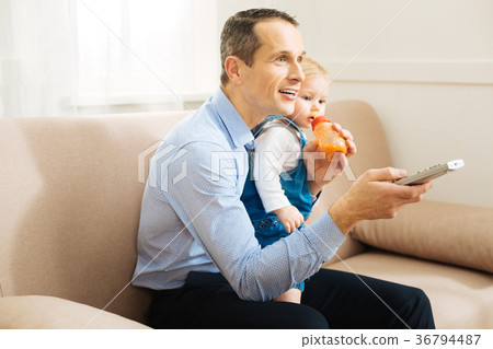 Positive young father feeling happy while watching Positive young father feeling happy while watching 36794487