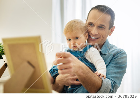 Smiling father holding a baby and pointing to the 36795029